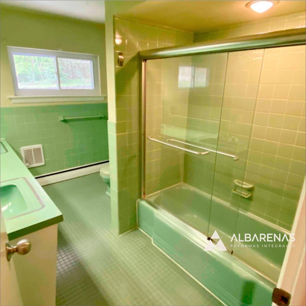 Baño antes de la reforma: revestimiento cerámico verde original de los años 70 y mampara corrediza envejecida